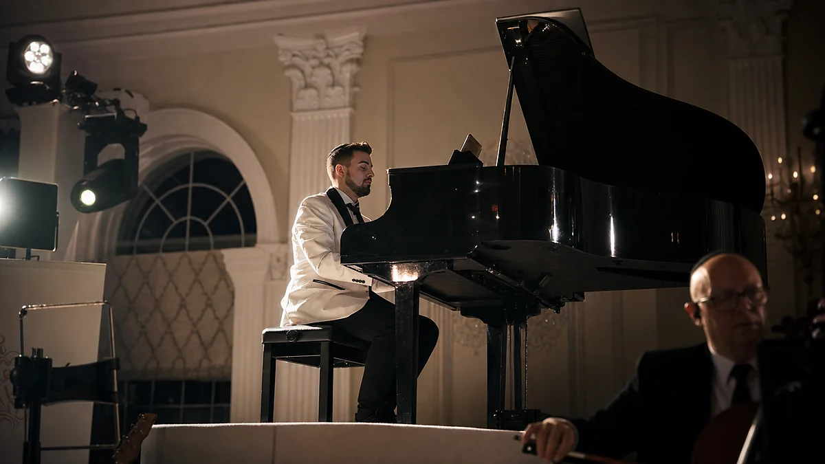 A pianist in a white dinner jacket at a grand piano on a softly lit ballroom stage
